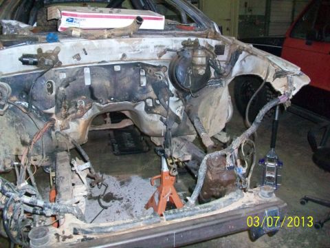 1999 Isuzu Vehicross - Vehicle engine bay disassembled, with various parts and wiring exposed. A red vehicle is visible in the background.