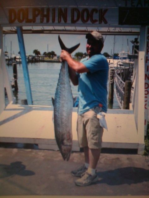 1989 Ford Bronco - Man proudly displays a large fish caught at Dolphin Dock, with boats visible in the harbor.