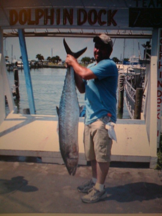 Man holding a large fish at Dolphin Dock with boats in the background