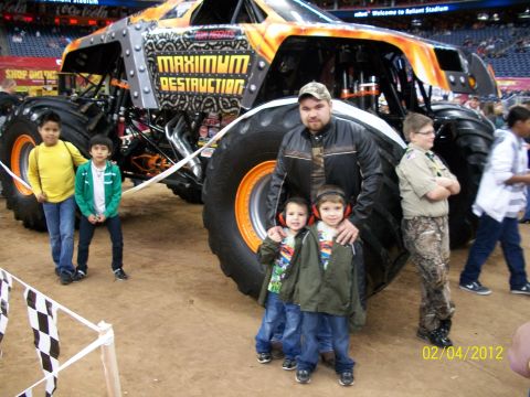 1989 Ford Bronco - A family poses in front of the 'Maximum Destruction' monster truck at an event.