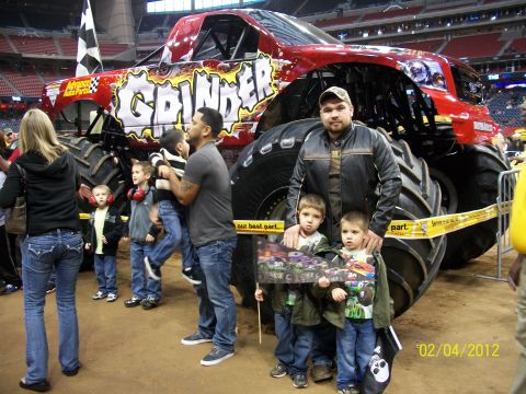 1989 Ford Bronco - A family poses in front of a large red monster truck named 'Grinder'.