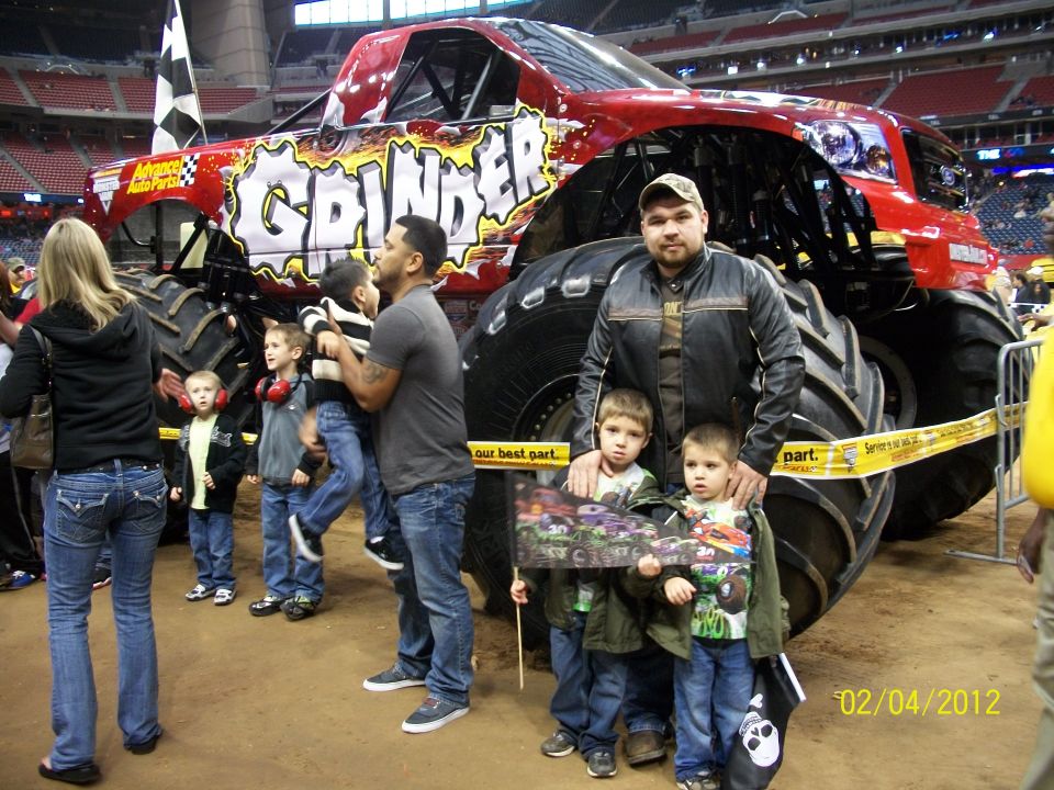 Red monster truck with 'Grinder' text, large tires, and a checkered flag