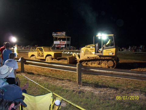 1989 Ford Bronco - A bulldozer helps a mud-covered vehicle out of a sticky situation during a nighttime event.