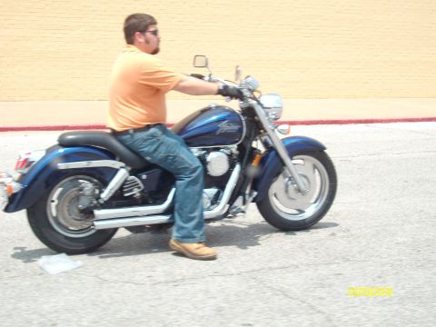 1989 Ford Bronco - A rider on a blue motorcycle is seen from the side, with a yellow brick wall in the background.