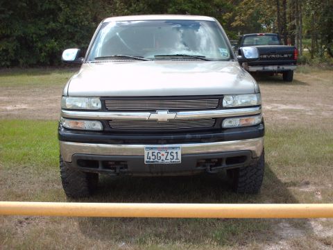 1989 Ford Bronco - A silver Chevrolet Silverado pickup truck is parked in a grassy area, with another truck in the background.
