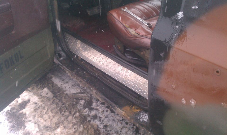 Interior of a vehicle showing a brown leather seat with a wrench on it, diamond plate trim, and a green door with text