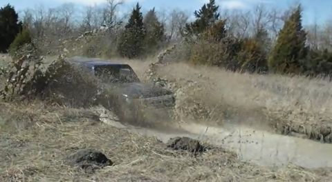 1995 Ford Bronco - SUV driving through a muddy trail with water splashing everywhere.