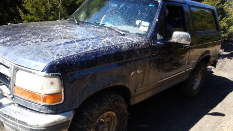 1995 Ford Bronco - Mud-splattered Ford Bronco seen from the front quarter angle.