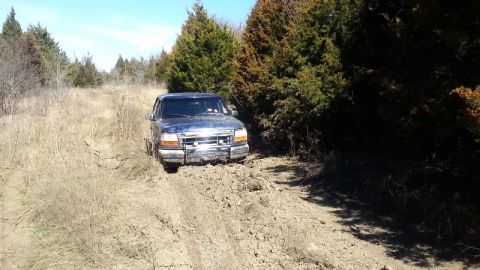 1995 Ford Bronco - Ford Bronco navigating a muddy trail through a wooded area.