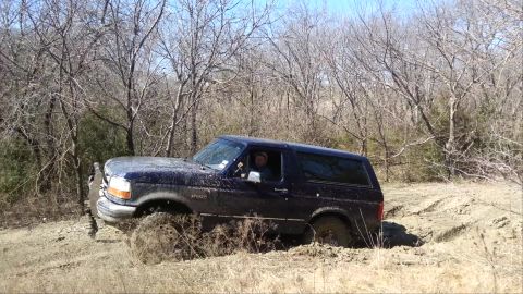 1995 Ford Bronco - This 1995 Ford Bronco is deep in the mud, navigating a challenging off-road terrain.
