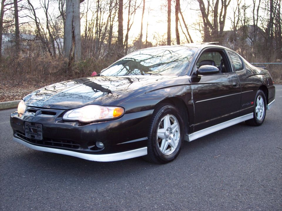 Black 2002 Chevrolet Monte Carlo parked on asphalt with trees in the background