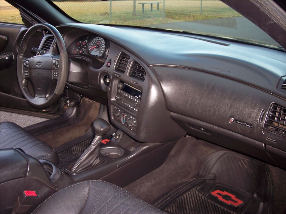 Interior view of a Chevrolet Monte Carlo showing the dashboard, steering wheel, center console, and seats. A badge on the dash reads 'Monte Carlo'