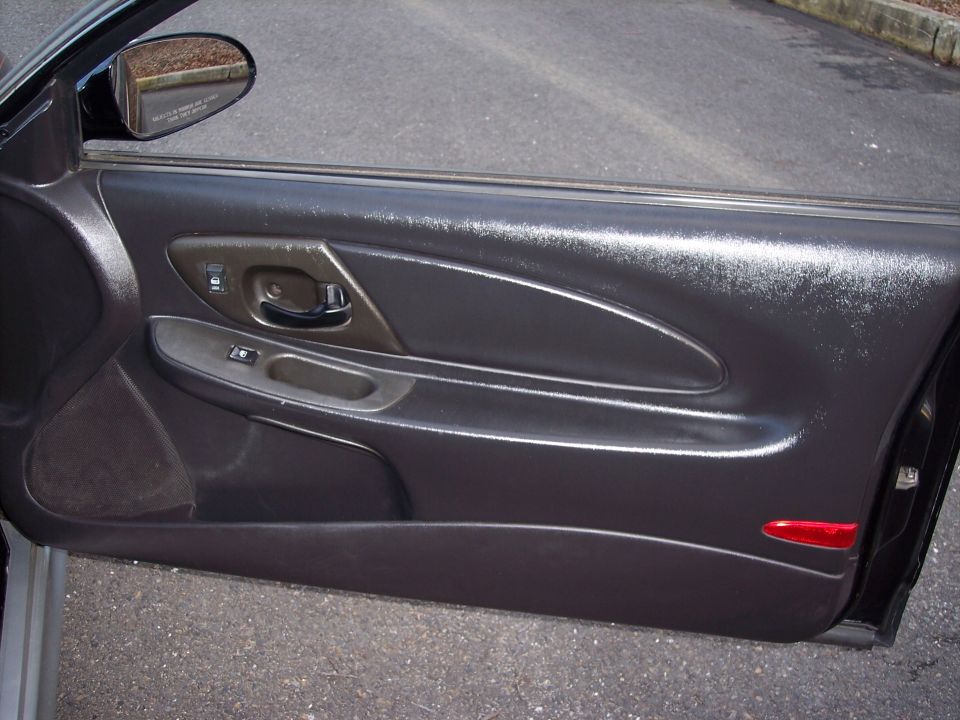 Interior of a car door, showing the armrest, door handle, and window controls