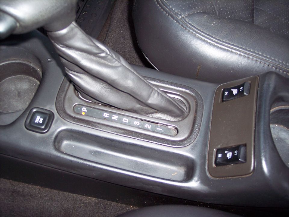 Car interior showing automatic gear shifter with P R N D 3 2 1 indicators and heated seat buttons