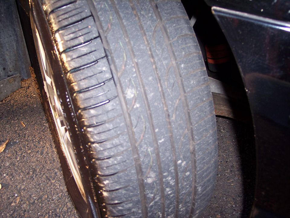 Close-up of a car tire with visible tread and sidewall details. Supermotors.net logo in lower right