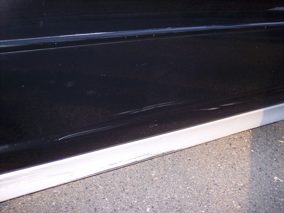 Black car door with scratches and silver trim
