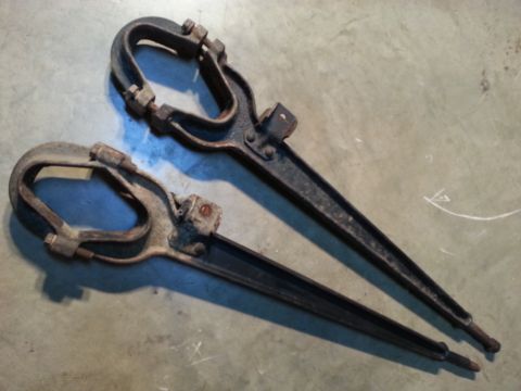 1995 Ford Bronco - Pair of old metal tools, possibly for automotive use, resting on a concrete surface.