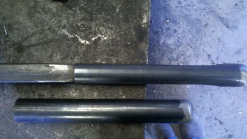 1996 Ford Bronco - Two metal tubes, one longer and tapered, are shown on a workbench.