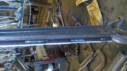 1996 Ford Bronco - A metal beam shows multiple welds and is surrounded by various tools and clamps in a workshop setting.