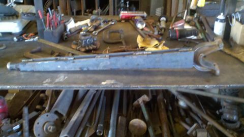 1996 Ford Bronco - A metal component rests on a workbench covered in various tools and equipment.
