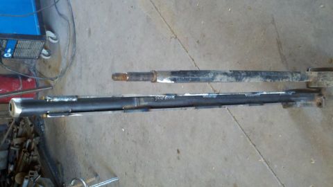 1996 Ford Bronco - Modified axle beam and steering knuckle are laid out on a concrete floor.