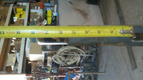 1996 Ford Bronco - A tape measure is shown extended over a metal tube in a cluttered workshop environment.