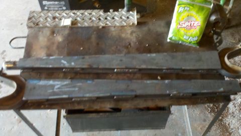 1996 Ford Bronco - Metal parts are laid out on a workbench next to a bag of chips.