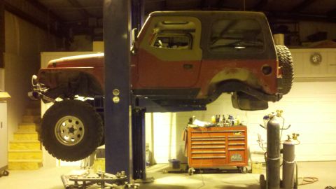 1996 Ford Bronco - Jeep Wrangler TJ undergoing service on a lift in a workshop environment.