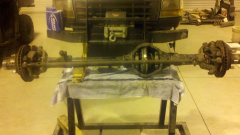 1996 Ford Bronco - A vehicle's front axle assembly is displayed on a table in a workshop setting.