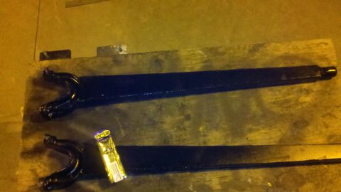 1996 Ford Bronco - Two black drive shafts are laid out on a wooden surface, with a yellow wrapper nearby.