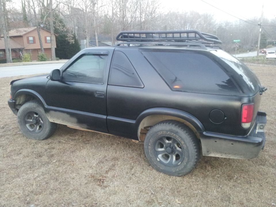 Black SUV with a roof rack, seen from the side and rear