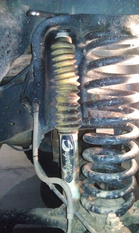 1993 Ford Bronco - Close-up view of a vehicle's suspension system, showing a shock absorber and coil spring.