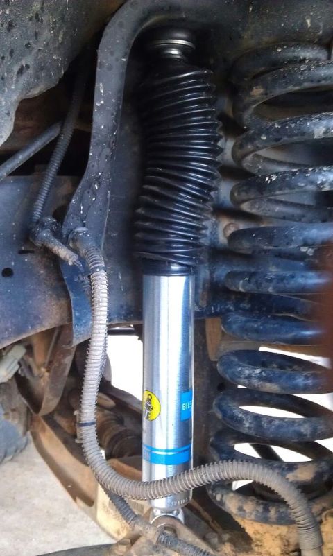 1993 Ford Bronco - Close-up view of a Bilstein shock absorber, a suspension component, with its characteristic black dust boot and blue branding.