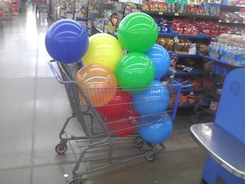 2003 Ford Crown Victoria - A shopping cart is full of blue, green, yellow, and orange balloons inside a retail store.