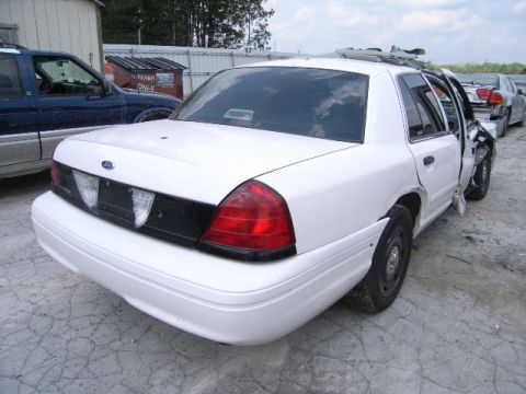 2003 Ford Crown Victoria - A damaged white 2003 Ford Crown Victoria is parked next to a blue SUV.