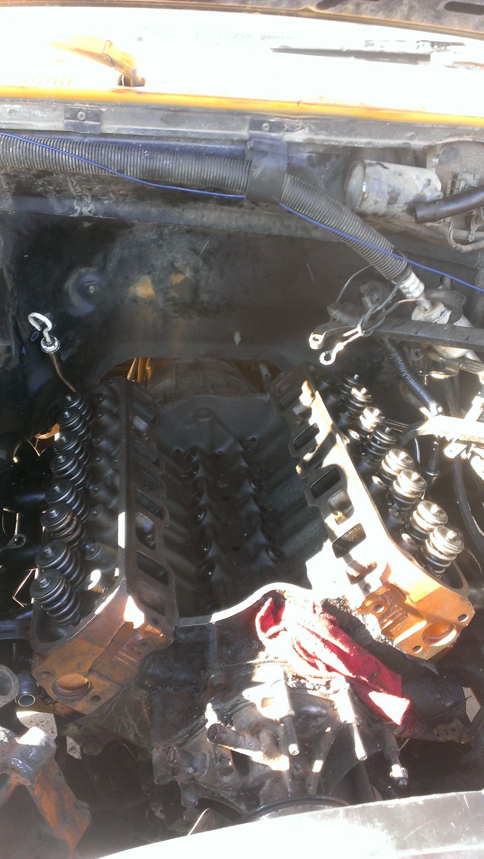 Engine bay with intake manifold removed, showing cylinder heads and valve train.