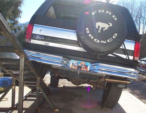 1996 Ford Bronco - Rear view of a black Ford Bronco full-size SUV with a black spare tire cover reading 'FORD BRONCO' and a bucking horse logo, showing chrome…