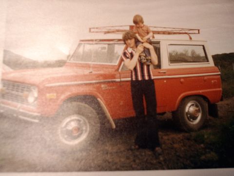 1996 Ford Bronco - A man and child stand next to a vintage red Ford Bronco.