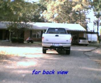 2000 Ford F-150 - Rear view of a 2000 Ford F-150 pickup truck in a driveway with a house and another vehicle in the background.