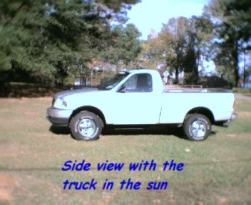 2000 Ford F-150 - This is a side view of a pickup truck parked on a grassy area with trees in the background.