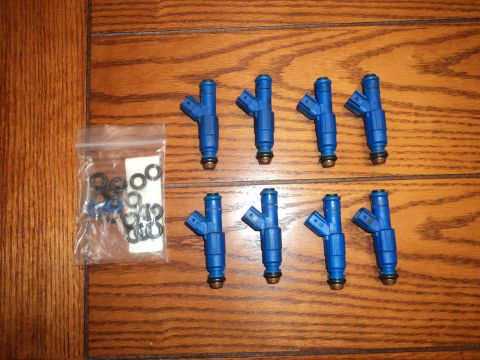 2004 Mercury Grand Marquis - A set of eight blue fuel injectors and assorted O-rings are laid out on a wooden table.