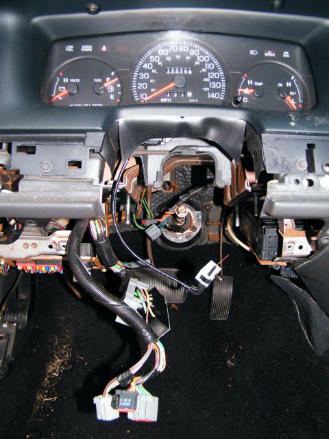 2004 Ford Crown Victoria - The dashboard of a car has been disassembled, revealing the wiring harness and steering column.