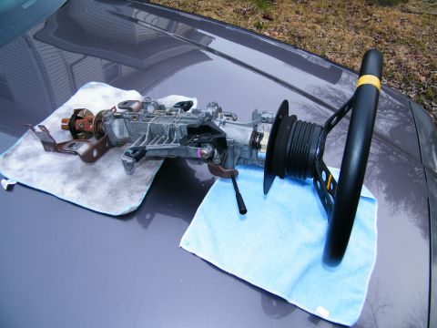 2004 Ford Crown Victoria - Disassembled steering column and steering wheel laid out on a car's hood.