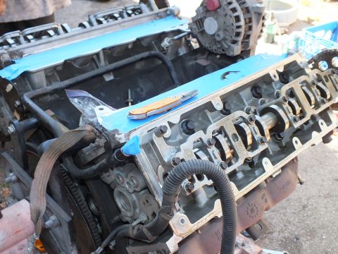 2003 Ford Crown Victoria - Top-down view of a cylinder head mating surface with a folding knife resting on the engine and blue tape nearby.