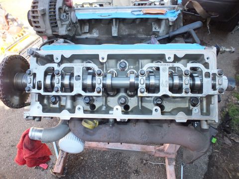2003 Ford Crown Victoria - Overhead view of a cylinder head showing camshaft and valves, with flywheel and red rag at left.