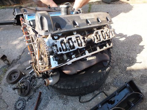 2003 Ford Crown Victoria - Engine on a tire with the plastic intake manifold lifted to expose the valley and lifters, valve cover nearby.
