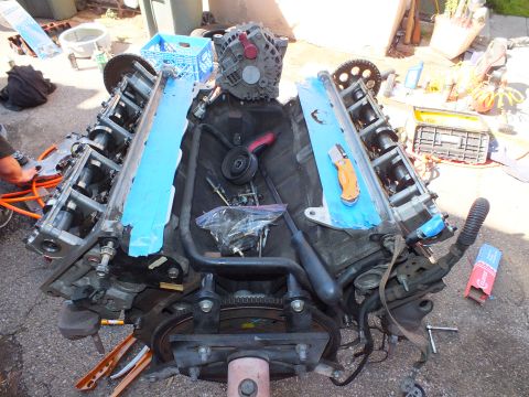 2003 Ford Crown Victoria - Engine block laid out during teardown, blue masking tape over ports and alternator resting on top.