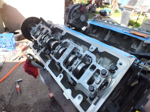 2003 Ford Crown Victoria - Close-up of an aluminum cylinder head showing camshaft, rockers and head bolts on a driveway.