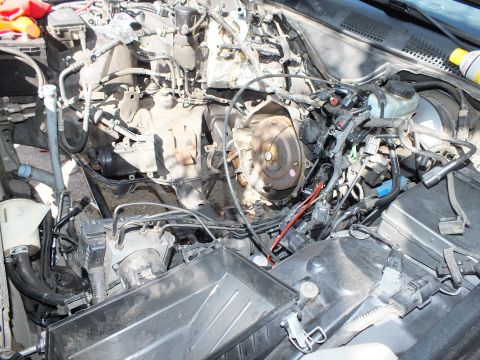 2003 Ford Crown Victoria - Open engine bay showing the bellhousing and disconnected wiring harness over a covered fender.