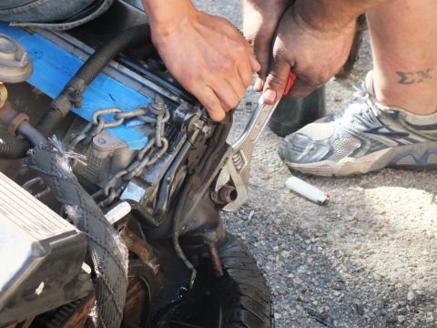 2003 Ford Crown Victoria - Close-up of hands working an adjustable wrench on a component at the rear of an engine.